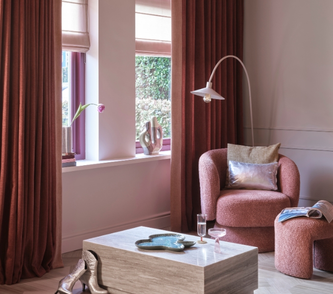 Woonkamer met relax stoel, salontafel en roest rode verduisterende overgordijnen en vouwgordijnen