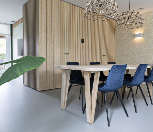 Keuken met houten 6-persoons eettafel, behang met bladpatroon en lichtgrijze marmoleum vloer