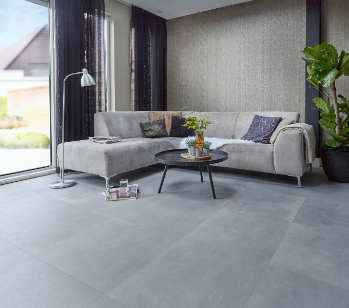 Woonkamer met lichtgrijze tegellook vloer WIJS, transparante gordijnen en beige hoekbank