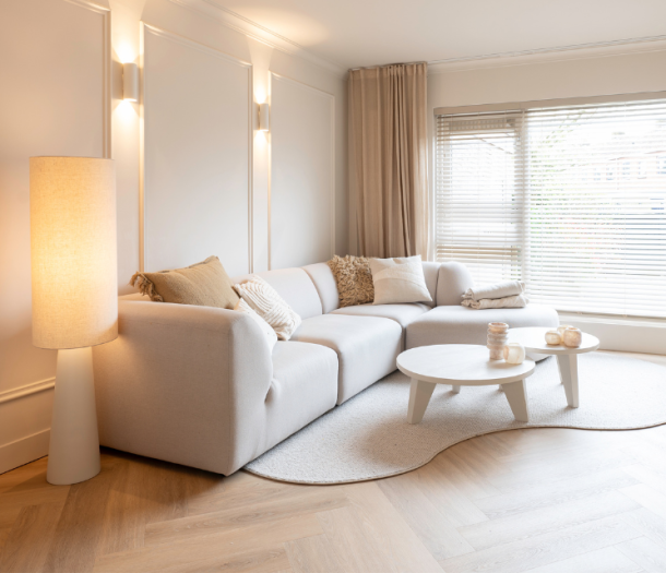 Witte horziontale jaloezieën en beige gordijnen in een scandinavisch woonstijl woonkamer met visgraat