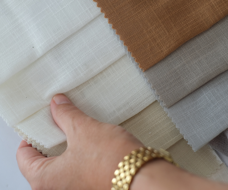 Verschillende kleuren stoffen zoals wit, grijs en bruin om te kiezen voor je raamdeco