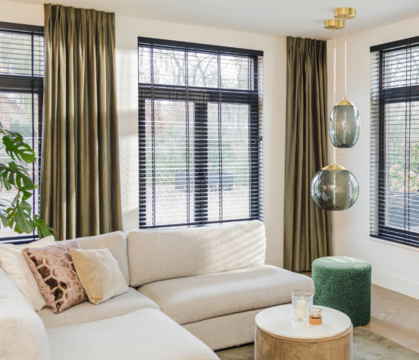 Donker groene gordijnen en zwarte jaloezieën in een hotel chic woonkamer